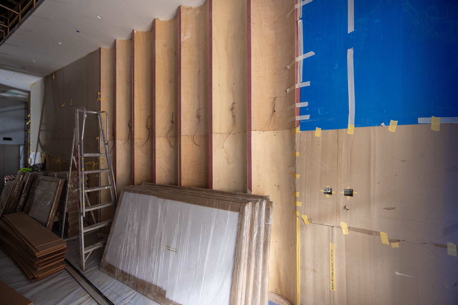 Pearl House By Imtiaz A construction site featuring exposed wooden walls, a ladder, and stacked plywood sheets in various stages of work.